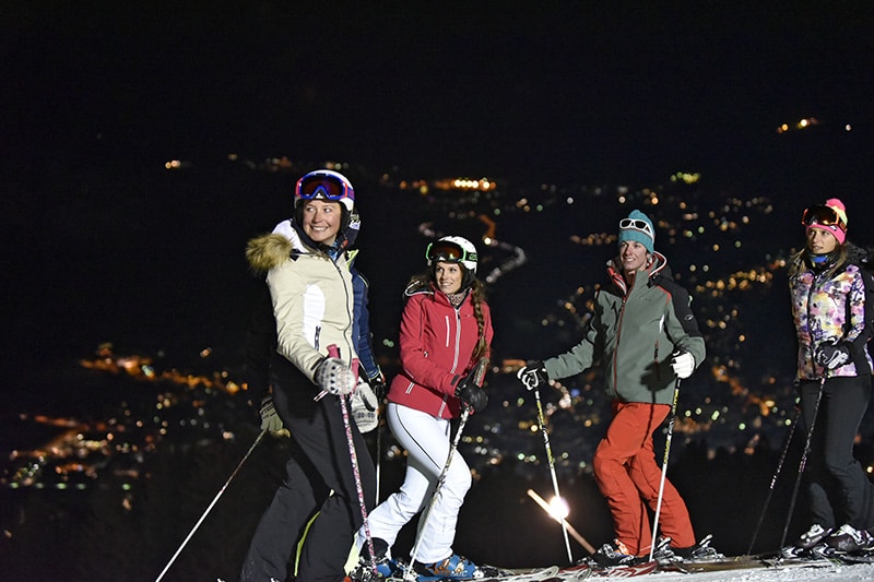 Lightened slope in Bormio: group of skiers