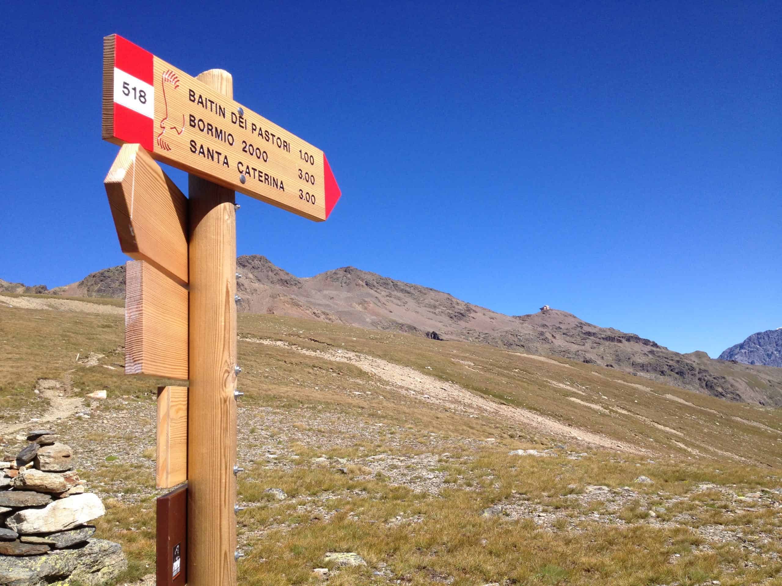 Un cartello in legno indica i panoramici sentieri della Valtellina.