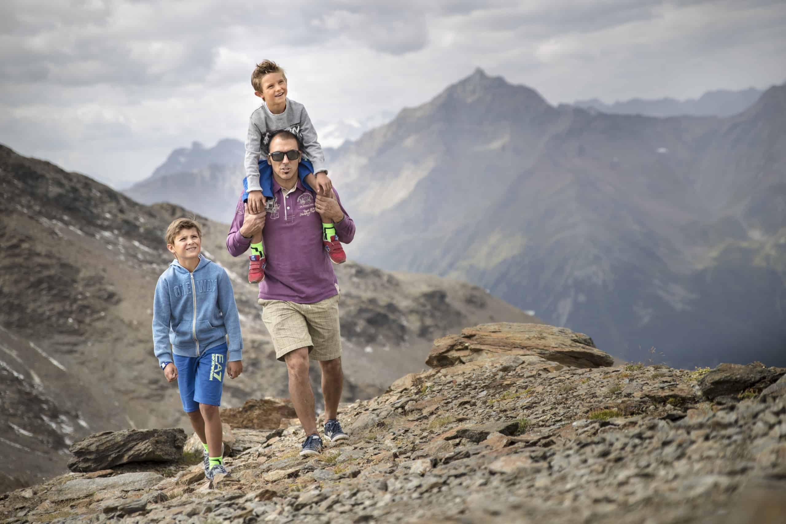 Un uomo e i suoi due figli fanno passeggiate in montagna.