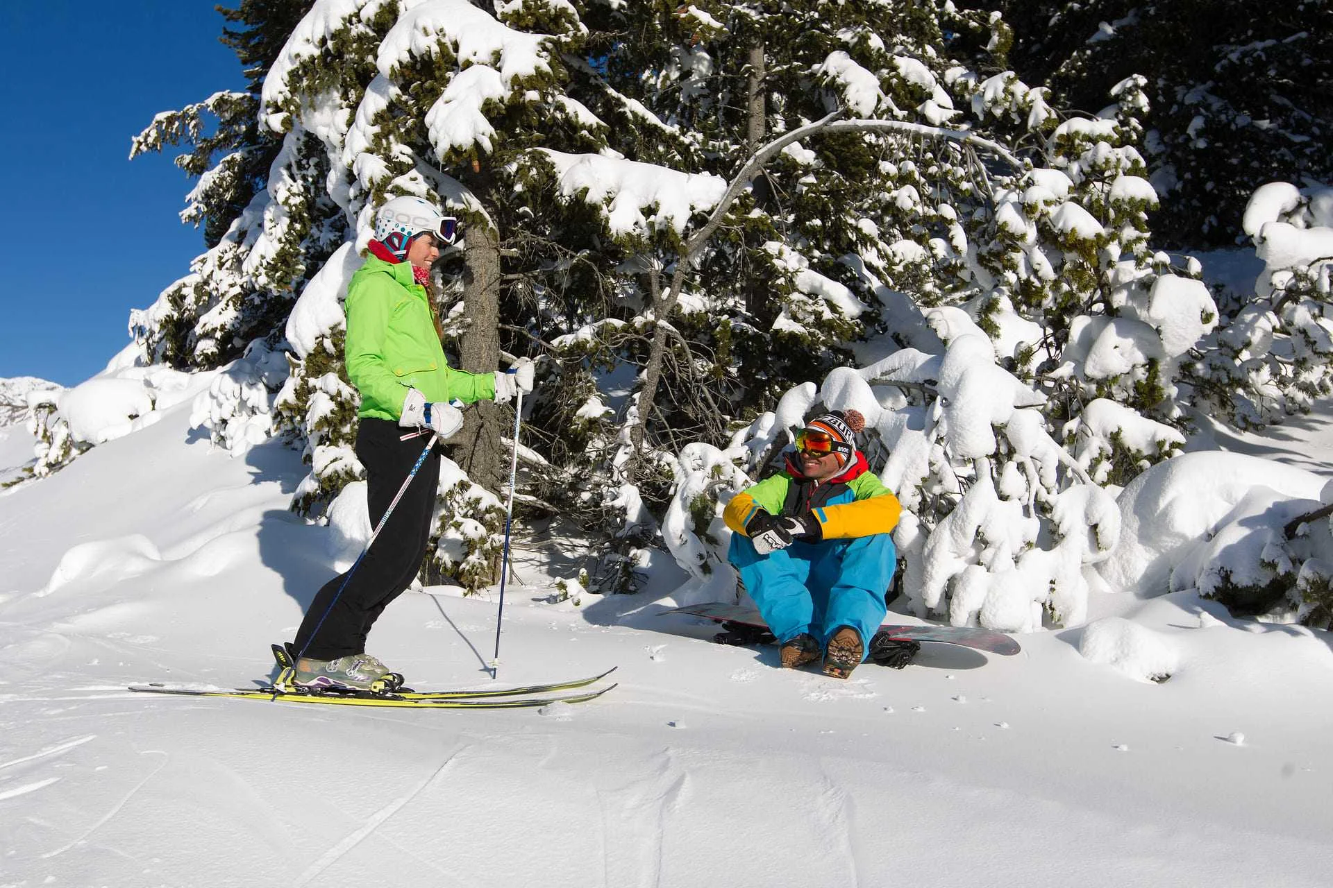 due persone indossano sci e snowboard e chiacchierano sulla neve