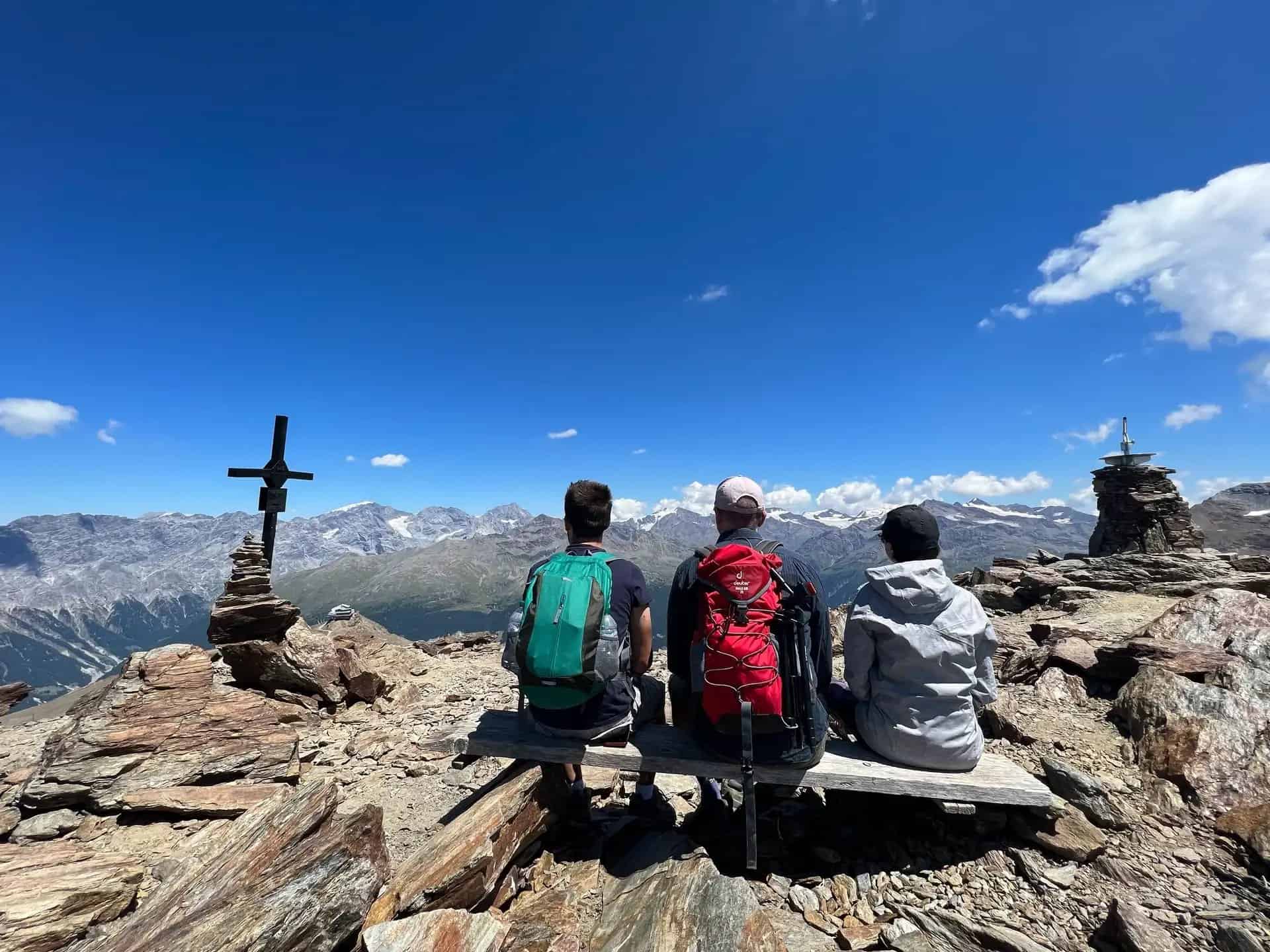 Quattro escursionisti seduti in cima a una montagna, si affacciano su un paesaggio panoramico per orientarsi.